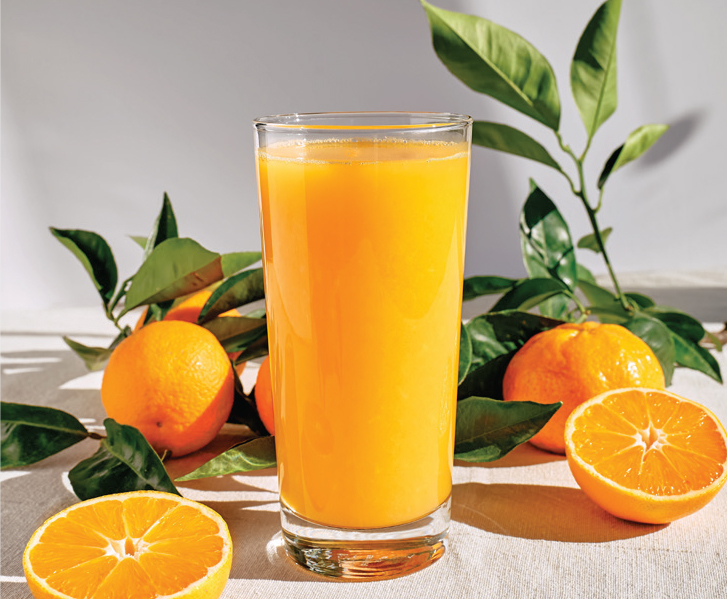Image of a glass of orange juice and oranges on a table